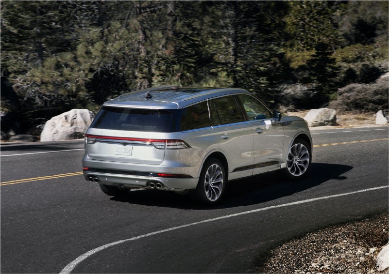 A 2023 Lincoln Aviator® Grand Touring model is shown being driven on a tight turn of a mountain road | Capital Lincoln of Wilmington in Wilmington NC